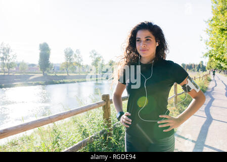 Sportliche junge Frau mit einer Unterbrechung am Flußufer Stockfoto