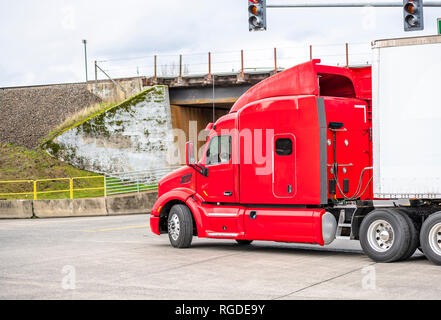 Big Rig hell rot Classic American modern Semi Truck mit hoher Kabine für die Fernbeförderung routs Transport Auflieger fahren auf der Straße der Stadt schneiden Stockfoto