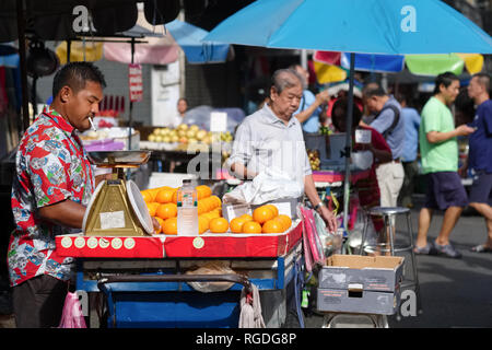 Eine orange Anbieter mit seiner Schubkarre in der Old Market, Chinatown, Bangkok, Thailand Stockfoto