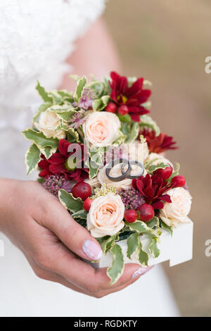 Schmuckschatulle mit Hochzeit Ringe mit frischen Blumen in der Hand der Braut eingerichtet Stockfoto