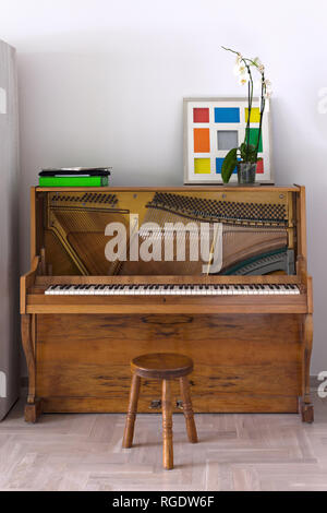 Akustischen Piano mit entfernten vorderen Abdeckungen und ein Stuhl, in einem Wohnzimmer, vertikal Stockfoto