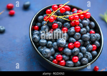 Schüssel gesunde organische Beeren mit Heidelbeeren und roten Johannisbeeren, frischen süßen Bio Beeren Top View Stockfoto