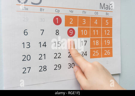 Kinder- Hand weist auf die lange Mai Ferien Urlaub in der Wand Kalender Stockfoto