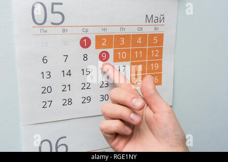 Die Hand weist auf die lange Mai Ferien Urlaub in der Wand Kalender Stockfoto