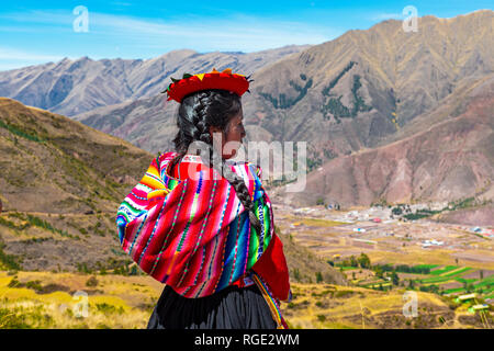 Junge Quechua indigene Frau in traditioneller Kleidung durch das Heilige Tal der Inka und Urubamba Tal in der Nähe von Cusco in den Anden, Peru. Stockfoto