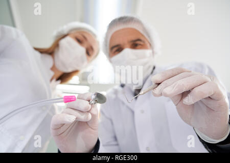 Zwei Ärzte, Patienten während der zahnmedizinischen Untersuchung. Männliche stomatologist Holding Restaurierung Instrumente oder Werkzeuge für die Zähne. Stomatolody Konzept. Stockfoto