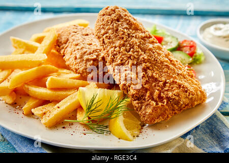 Knusprige Fisch Filet gebraten in ein Bier, Gebäck oder Teig und serviert mit frischen Zitronenscheiben und Kartoffelchips in der Nähe zu sehen. Stockfoto