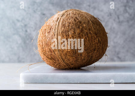 Frische organische Brown Raw Coconut auf weißem Marmor. Ökologische Lebensmittel. Stockfoto