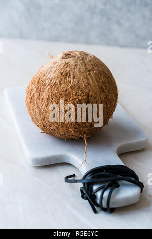 Frische organische Brown Raw Coconut auf weißem Marmor. Ökologische Lebensmittel. Stockfoto