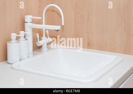 Moderner weißer Hahn und Keramik Waschbecken. Minimalistische Badezimmer Details im Innenraum Stockfoto