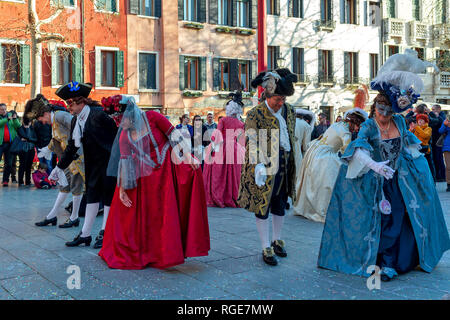 Gruppe von Menschen, die typischen Kostüme und Masken tanzen auf kleinen Platz während der berühmten traditionellen Karneval in Venedig. Stockfoto