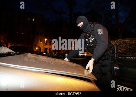 Berlin, Deutschland. 29 Jan, 2019. Ein Polizist öffnet die Motorhaube eines Fahrzeugs während einer Operation in Kreuzberg nach einem Ueberfall auf einen Geldtransporter im Oktober. Etwa drei Monate nach dem spektakulaeren Ueberfall auf einen Geldtransporter in der Nähe von Alexanderplatz, rund 180 Polizisten durchsuchten die Wohnungen von Verdächtigen. Die Mission in Tempelhof, Steglitz und Kreuzberg auch Offiziere der Special Operations Command (SEK), wie ein Sprecher der Polizei am Dienstag Morgen sagte. Credit: Christoph Soeder/dpa/Alamy leben Nachrichten Stockfoto