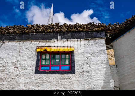 Weiß gestrichene Fassade eines traditionellen Haus in Upper Mustang, mit einem bunten Fenster und Brennholz gespeichert auf dem Dach Stockfoto