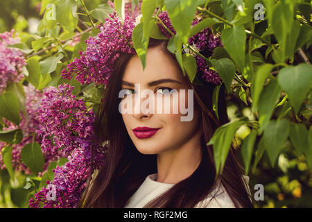 Fröhliche Frau mit Blumen im Freien. Junge perfekte Weibliche Model in der Blüte Garten Stockfoto