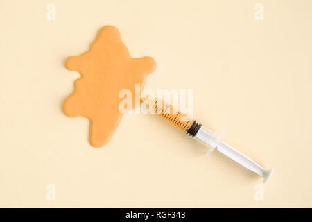 Hohe Betrachtungswinkel von Spritze und Beize gegen gelben Hintergrund minimal kreatives Konzept. Stockfoto