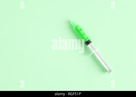 Flach der Spritze auf grünem Hintergrund minimal kreatives Konzept isoliert. Platz für Kopieren. Stockfoto