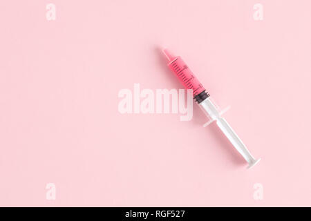Flach der Spritze auf rosa Hintergrund minimal kreatives Konzept isoliert. Platz für Kopieren. Stockfoto