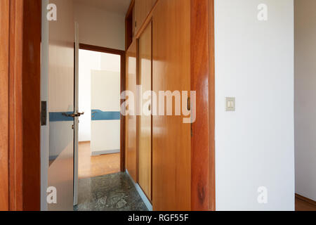 Flur mit Kleiderschrank aus Holz und offene Tür, innen im Landhaus Stockfoto