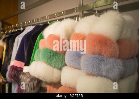 Fancy und bunten weiblichen Pelzmäntel auf Kleiderbügeln im Shop zum Verkauf. Stockfoto