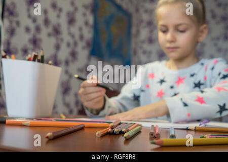 Aufmerksame Kind schreibt mit Buntstiften auf dem Album. Hausaufgaben. Die Kreativität der Kinder. Stockfoto