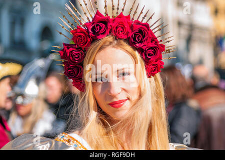 Venedig, Italien - 10 Februar 2018: Porträt einer schönen blonden jungen kaukasischen Frau eine Krone trägt der roten Rosen während des Venezianischen Karnevals party Stockfoto