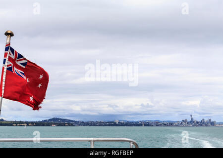 Etwas zerlumpten Neuseeland Flag auf der Fähre, der Hafen von Auckland, mit Schiff und Bahn in das Wasser zurück in die Stadt Auckland führenden, inclu Stockfoto