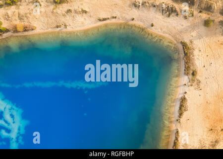 Abstrakte Luftbild von einem tiefen Blau Kiessee in dem Sand für die Bauindustrie abgebaut ist. Stockfoto