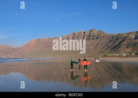 Reflexion der Klippe von Famara mit Surfer an der Playa de Famara. Stockfoto