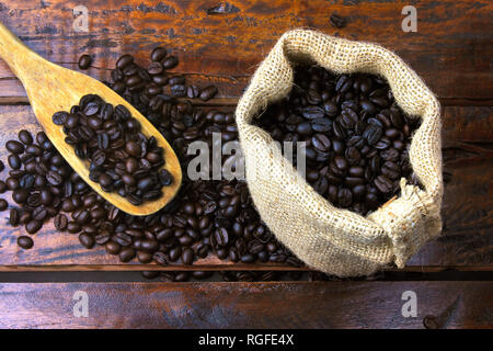 Geröstet und frisch gemahlenen Bohnen in rustikalen Stofftasche und in rustikalen Holztisch gegossen. Ansicht von oben Stockfoto