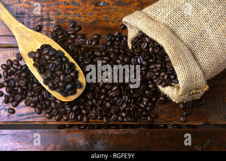 Geröstet und frisch gemahlenen Bohnen in rustikalen Stofftasche und in rustikalen Holztisch gegossen. Ansicht von oben Stockfoto