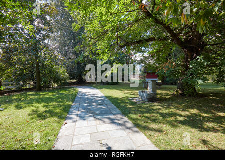 Stein Fliesen- Pfad mit Garten- und Kastanienbäumen in einem sonnigen Sommertag, Italien Stockfoto