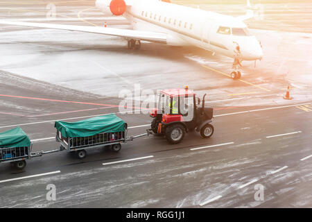 Fracht Fracht Traktor Maschine liefern Gepäckwagen mit dem Flugzeug am Flughafen. Flughafenbetreiber und Service. Stockfoto