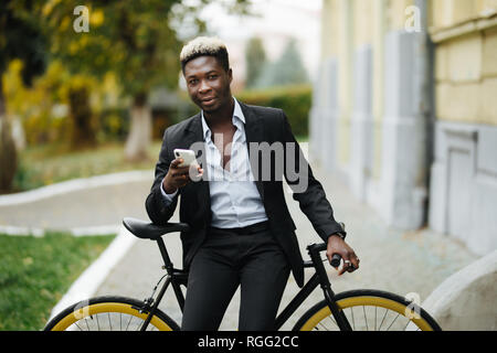Hipster Mann mit Fahrrad Senden der Nachricht auf dem Mobiltelefon in der Stadt Stockfoto