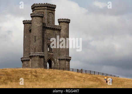 Zwei Wanderer (ein Mann und eine Frau) und ihr Hund Ansatz Paxton's Tower in Llanarthne, Carmarthenshire Stockfoto