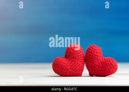 Valentines Tag Konzept. Hand machen zwei Garne rotes Herz auf Holztisch und blauer Hintergrund Stockfoto