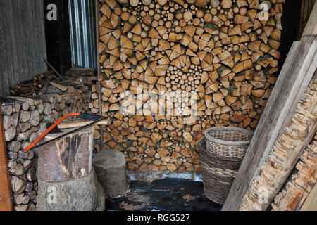 Ungewürzt brennholz Luft Trocknen im Holzschuppen. Stapel frisch geschnitten und split Feuer Holz mit Herz Form mit kontrastierenden Umläufe und Splits gebaut. Stockfoto