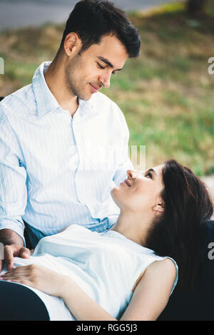 Junge Frau liegt auf dem mans Knie und Suchen, auf ihn lächelnd. Happy people portrait. Stockfoto