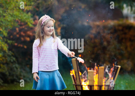 Kind mit SMORES am Lagerfeuer. Kinder braten Marshmallow auf Stick am Lagerfeuer. Herbst Familie Spaß im Freien. Camping mit Kindern im Herbst Wald. Wenig gi Stockfoto