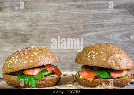 Zwei Sandwiches mit Lachs, Gurken und Kräuter mit Kopie Speicherplatz auf rustikalen Holzmöbeln Hintergrund Stockfoto