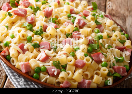 Traditionelle italienische pasta Ditalini mit grünen Erbsen, Schinken und Käse closeup auf einem Schild an einem Holztisch. Horizontale Stockfoto