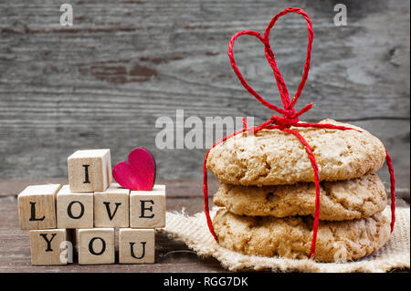 Ich liebe dich Inschrift und hausgemachte oat Cookies mit Herzförmigen red ribbon auf hölzernen Tisch gebunden. Valentines Tag Konzept Stockfoto