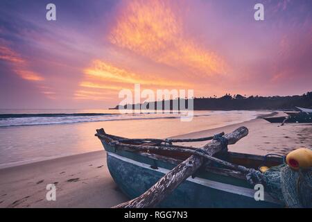 Fischerboot auf dem Sand strand gegen Bunte sunrise in der Nähe von Tangalle in Sri Lanka. Stockfoto