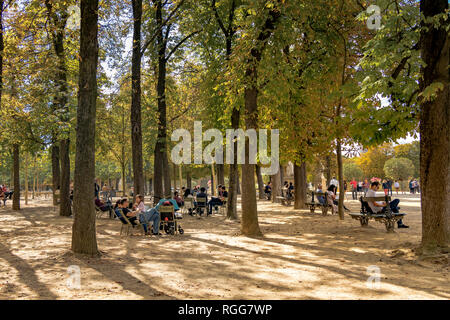 Leute sitzen auf Bänken und Stühlen im Schatten der Bäume an einem heißen Sommertag im Jardin du Luxembourg, Paris, Frankreich Stockfoto