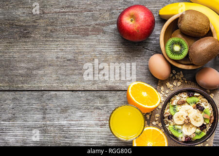 Gesundes Frühstück mit Hafer, Früchte, Beeren, Eier und Orangensaft auf rustikalen Holzmöbeln Hintergrund mit Kopie Raum. top View Stockfoto