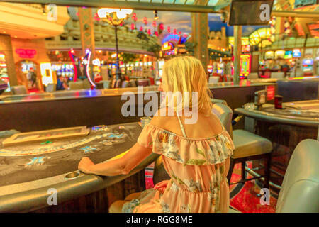 Rückseite der kaukasischen blonde Frau spielen im Casino mit hellen Lichtern. Lifestyle Mädchen warten an Blackjack in Las Vegas, Nevada, United zu spielen Stockfoto