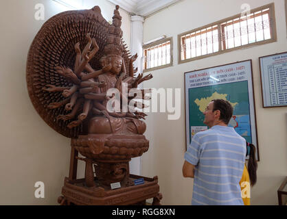 Touristen an einer hinduistischen hölzerne Skulptur mit Blick auf das historische Museum in Ho Chi Minh City, Vietnam, Asien Stockfoto