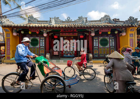 Menschen Reiten Fahrräder vor der Quan Cong Tempel aka Chua Ong Pagode in Hoi An, Vietnam Stockfoto