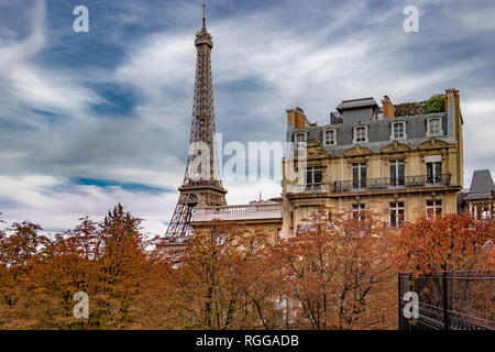 Der Eiffelturm sitzt hinter einem Grand Paris Wohnung Gebäude wie von der Avenue de Camoens mit den Bäumen drehen Ein herbstliches orange Farbe gesehen, Paris Stockfoto