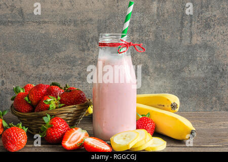 Frische Erdbeeren und Bananen Smoothie in einer Flasche auf rustikalen Holztisch. gesundes Getränk Stockfoto