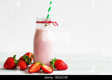 Strawberry Smoothie oder milchshake in einer Flasche mit Stroh mit frischen Beeren auf weißem Holz- Hintergrund. Gesunde Nahrung für b Stockfoto